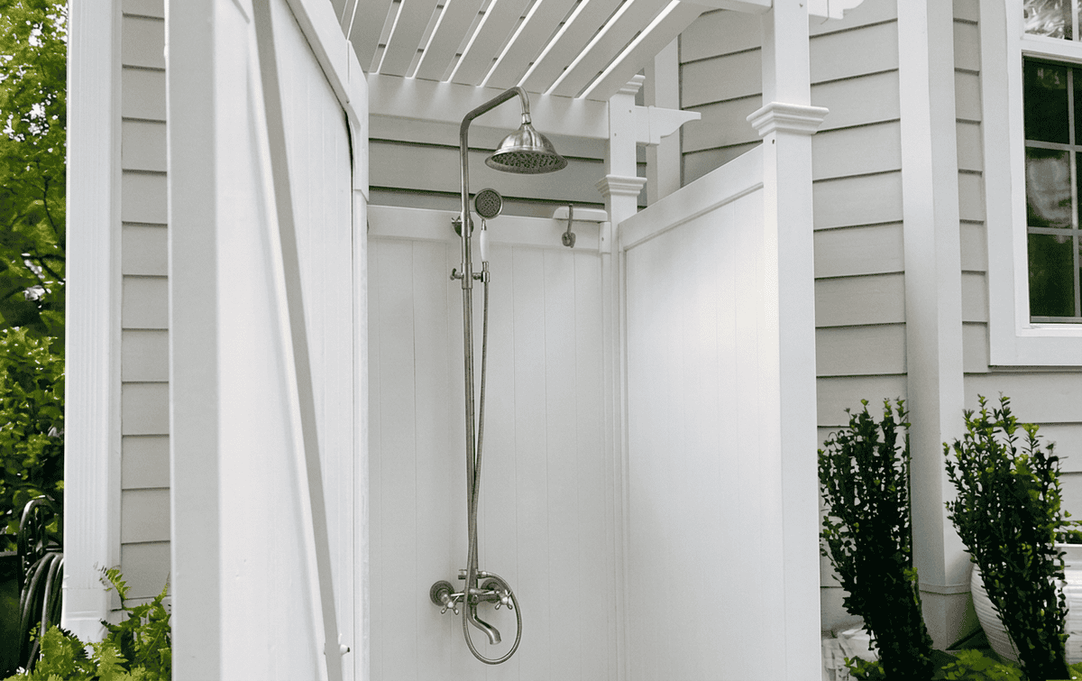 Outdoor shower enclosure with rain shower head and privacy wall.