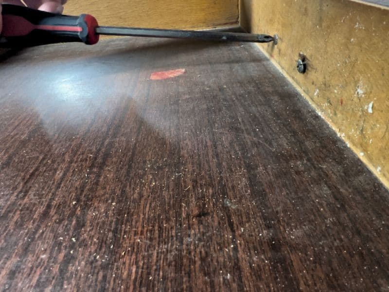 Removing hardware from a wood desk before refinishing
